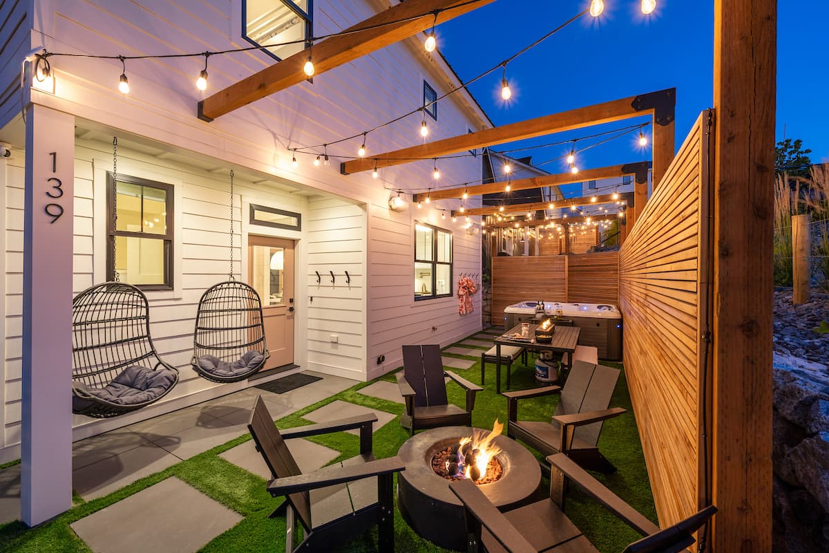 Private courtyard with firepit, hot tub, and string lights at dusk